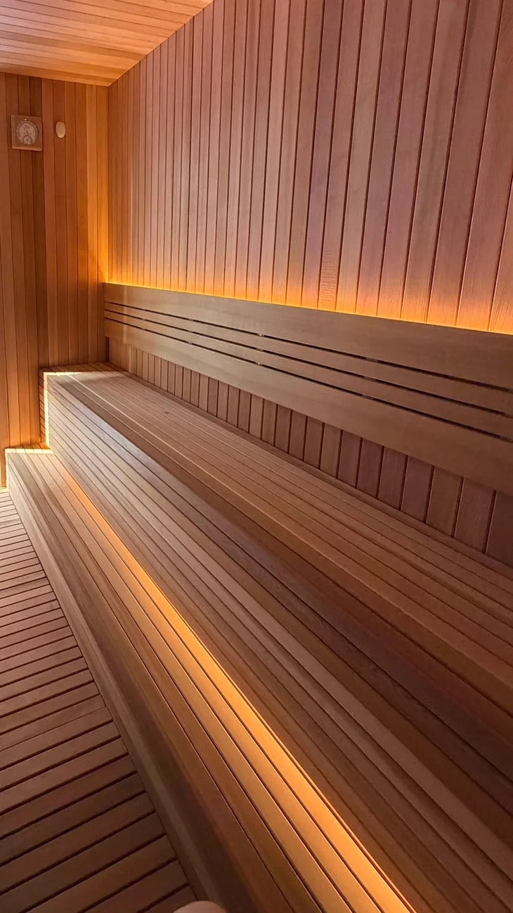 Inside a finished sauna: clear cedar walls, ceiling and benches, lit under the benches